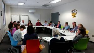 Faculty and staff sitting around a rectangular table talking over lunch